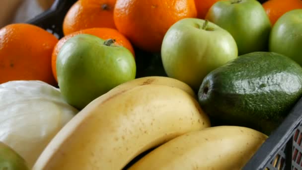 Kadın eli, avokado ve elma alır. Meyve ve sebzeli kutu yakın. Coronavirus salgını ve sosyalleşme sırasında yiyecek dağıtım hizmetleri. İnternetten alışveriş. Yemek Bağışı — Stok video
