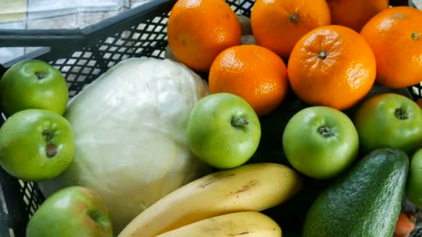Caja llena con frutas y verduras plátanos manzanas mandarinas repollo de aguacate de cerca. Servicios de entrega de alimentos durante la pandemia de coronavirus y distanciamiento social. Compras en línea. Comidas Donaciones de alimentos — Vídeos de Stock