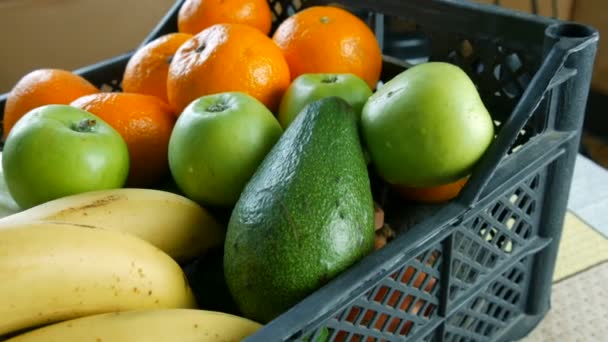 Volle Schachtel mit Obst und Gemüse Bananen Äpfel Mandarinen Avocado Kohl aus nächster Nähe. Essenslieferdienste während der Coronavirus-Pandemie und soziale Distanzierung. Online einkaufen. Essensspenden — Stockvideo