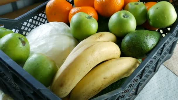 Caixa cheia com frutas e legumes bananas maçãs tangerinas repolho de abacate close up. Serviços de entrega de alimentos durante a pandemia de coronavírus e distanciamento social. Compras online. Refeições Doações de alimentos — Vídeo de Stock