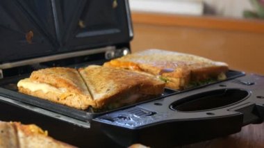 Ev mutfağında sabah kahvaltısı. Pastırmalı sandviç, çedar peyniri ve marul özel bir tost makinesinde ya da sandviç makinesinde kızartılır.