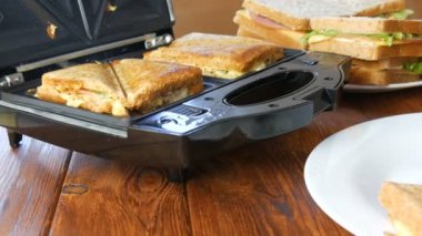 Ev mutfağında sabah kahvaltısı. Pastırmalı sandviç, çedar peyniri ve marul özel bir tost makinesinde ya da sandviç makinesinde kızartılır. Özel mutfak spatulası taze sandviç ekmeği alır.