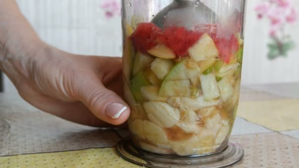 Batidora de mano en la cocina del hogar. Las manos de las mujeres hacen un batido rojo saludable de plátanos, manzanas y fresas. Comida Vegana Saludable, Dieta de Alimentos Crudos . — Vídeos de Stock