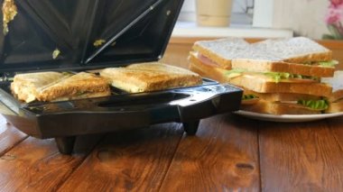 Ev mutfağında sabah kahvaltısı. Pastırmalı sandviç, çedar peyniri ve marul özel bir tost makinesinde ya da sandviç makinesinde kızartılır.