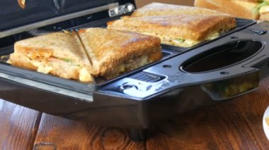 Ev mutfağında sabah kahvaltısı. Pastırmalı sandviç, çedar peyniri ve marul özel bir tost makinesinde ya da sandviç makinesinde kızartılır.