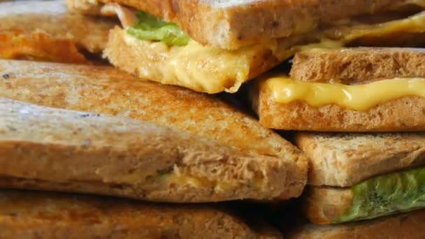Ранковий сніданок на домашній кухні. Бутерброди або тостери з беконом, сиром чеддер і салатом обертаються ближче . — стокове відео