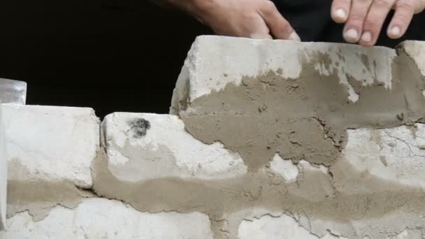Manliga händer av en byggare lägga en tegelsten på färsk våt cement. En rad av vit tegelsten på en byggarbetsplats med närbild. Vägg — Stockvideo