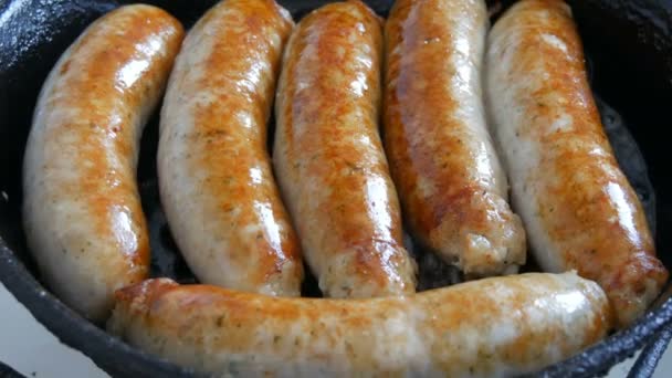Thick fatty delicious fresh sausages are fried in a pan in the home kitchen. Fried meat products making sausages for beer. White Munich or Bavarian sausages — Stock Video