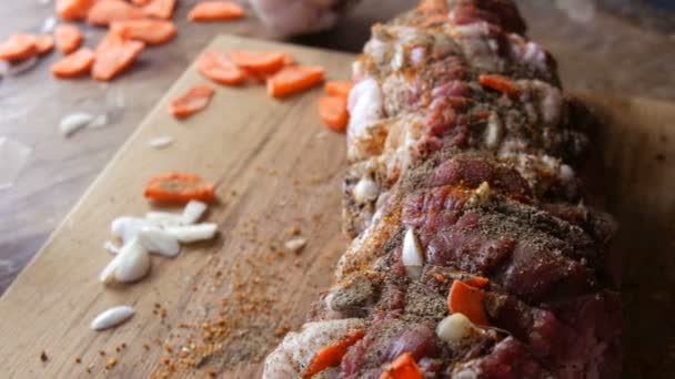 Frisch saftige Stück rohes Fleisch Schweinefleisch Steak oder Speck mit Gewürzen von Pfeffer, Knoblauch, Karotten in einem rustikalen Stil mit Backfäden im Ofen gesalzen und gewürzt, garniert auf Holzuntergrund aufgewickelt — Stockvideo