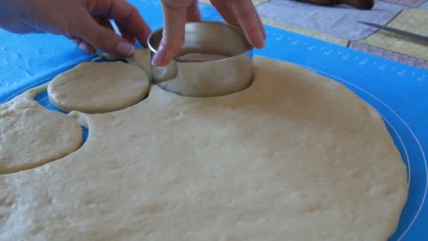 As mãos femininas fazem formas para futuros donuts com um anel redondo especial em um tapete de silicone especial para amassar a massa. Tecnologia moderna na cozinha — Vídeo de Stock