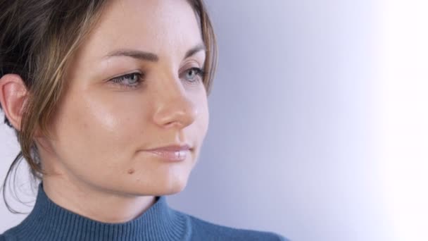 Portrait of a beautiful happy young woman or girl with blond hair and green eyes looking seriously and thoughtfully to the side on a white background — Stock Video