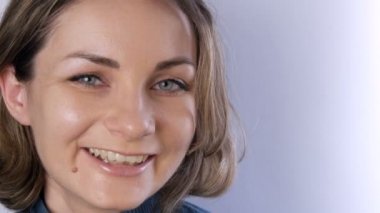 Kısa saçlı, yeşil gözlü, gülümseyen ve beyaz arka planda kameraya bakan güzel, mutlu genç bir kadının portresi.