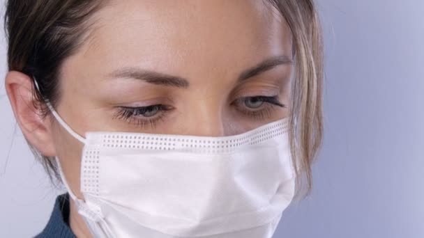 Portrait Beautiful young woman with tousled hair with tired eyes in medical mask on a white background close-up view. Nurses, medical staff during epidemic. Health care Coronavirus and medical concept — Stock Video