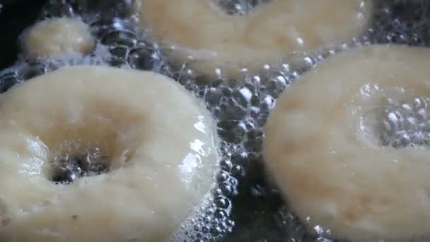 Deliziose ciambelle fritte in una padella. Le ciambelle grandi sono fritte in olio caldo in una pentola. Cottura fatta in casa — Video Stock