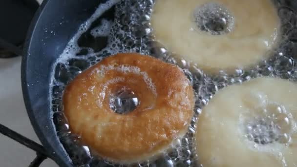 맛있는 도넛 이 프라이팬에서 튀기고 있습니다. 큰 도넛을 냄비에 넣고 뜨거운 기름에 튀 깁니다. 집에서 구운 빵 — 비디오