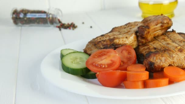 Tasty juicy fresh slices of grilled steak entrecote pork meat next to cherry tomatoes and fresh vegetables cucumbers on a white restaurant plate — Stock Video