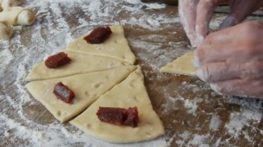 Hamuru kruvasana çevir. Ev yapımı tatlı hamur işleri. Reçel, hamuru kadın eli yaptı. Ev mutfağında reçelli kurabiye yapan eller.