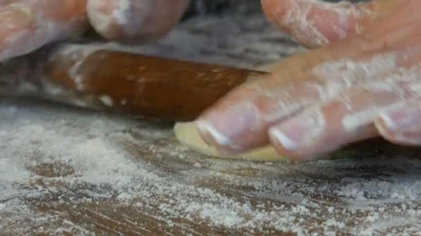 Las manos femeninas de los panaderos despliegan la masa con un delgado rodillo de madera en la cocina del hogar. Pasteles frescos caseros deliciosos de cerca vista . — Vídeos de Stock