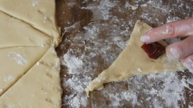 Hamuru kruvasana çevir. Ev yapımı tatlı hamur işleri. Reçel, hamuru kadın eli yaptı. Ev mutfağında reçelli kurabiye yapan eller.