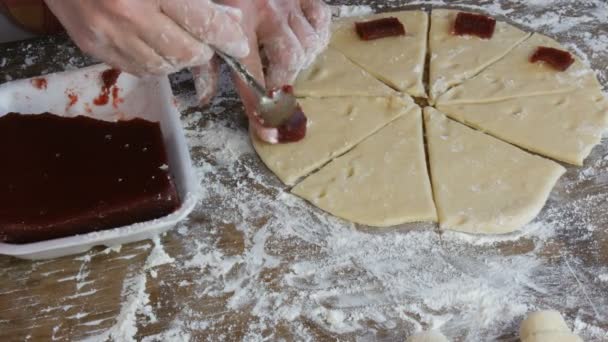 Weibliche Hände lagen mit einem Teelöffel in einem Kreis Scheiben Kirschmarmelade auf rohem Teig für zukünftige Croissants. Hausgemachtes Gebäck. Marmelade, der Teig, von Frauenhand in der heimischen Küche gemacht — Stockvideo