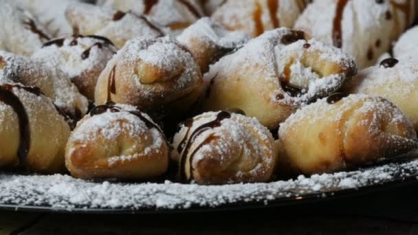 Čerstvě upečené domácí croissanty s třešňovým cukrem nalité čokoládovou polevou na velký talíř v kuchyni — Stock video
