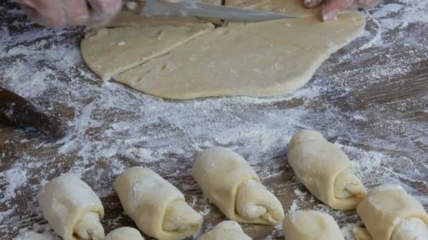 Samičí ruka krájí těsto nožem. Syrové croissanty v řadě. Domácí sladké pečivo. Džem, těsto, dělané ženskou rukou v kuchyni — Stock video