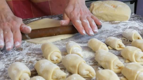 Bakkers vrouwelijke handen rollen het deeg uit met een dunne houten deegroller in de huiskeuken. Zelfgemaakte verse heerlijke gebakjes. — Stockvideo