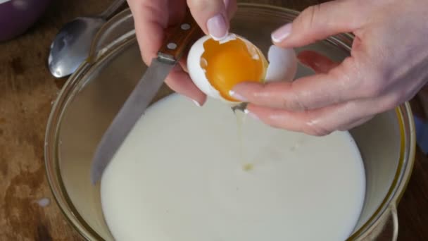 Amassar casa fazendo massa. As mãos femininas quebram ovos crus em leite em um recipiente transparente especial — Vídeo de Stock