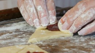 Hamuru kruvasana çevir. Ev yapımı tatlı hamur işleri. Reçel, hamuru kadın eli yaptı. Ev mutfağında reçelli kurabiye yapan eller.