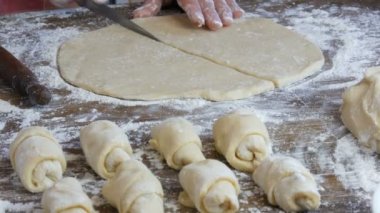 Kadın eli, hamuru bıçakla kesiyor. Arka arkaya çiğ kruvasan. Ev yapımı tatlı hamur işleri. Reçel, hamur, ev mutfağında kadın eli ile yapıldı.