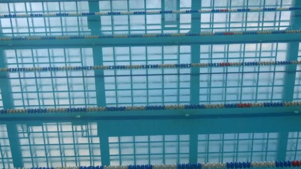 Prázdný bazén s klidným odrazem denního světla a čistou vodou a tratí pro koupání. Modrá voda v bazénu. Prázdné stezky se závodními pruhy — Stock video