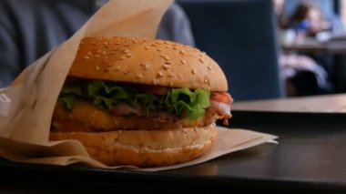 Fast food restoranında masada nefis sulu taze burger. Salata yaprakları, taze çörek, et pirzolası, sağlıksız sos.