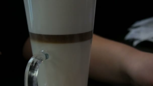 Delizioso latte appena fatto su un tavolo in un caffè. Schiuma di latte da caffè di latte in un bicchiere speciale lungo trasparente. Caffè sedimenti miscele e rende modelli insoliti — Video Stock