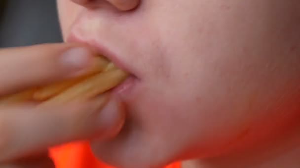 En tonåring äter pommes frites med sås. Ansikte och mun närbild. Ohälsosam snabbmat — Stockvideo