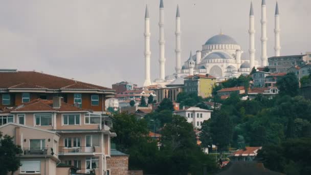 Konut alanlarının arka planında büyük, güzel bir beyaz cami. Deniz manzarası ve oradan geçen bir turist teknesi. İstanbul, Türkiye — Stok video