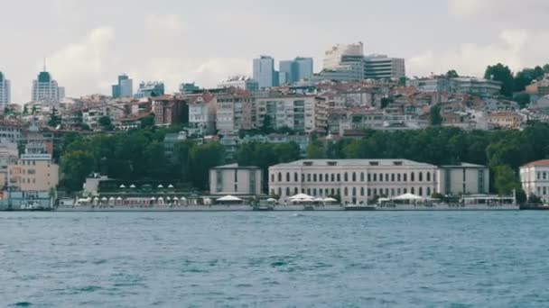 Istambul, Turquia - 12 de junho de 2019: Bairro de luxo rico de edifícios residenciais em colinas verdes na costa que estão cercados por vegetação. Vista de um barco que passa — Vídeo de Stock