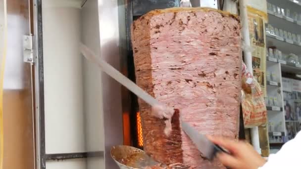 Istambul, Turquia - 11 de junho de 2019: cozinhe corta carne para fazer shawarma, giroscópios, kebab doner. Cozinhar carne no espeto — Vídeo de Stock