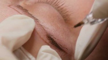 Güzellik salonunun yakın görüntüsünde kaşların şeklini düzeltiyorum. Mikro patlayıcı, kalıcı makyaj, kalıcı makyaj, barut püskürtme.