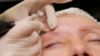 Güzellik salonunun yakın görüntüsünde kaşların şeklini düzeltiyorum. Mikro patlayıcı, kalıcı makyaj, kalıcı makyaj, barut püskürtme.