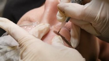 Ustanın eli kalıcı makyaj yapıyor. Toz püskürtme ile modern bir kaş düzeltme yöntemi. Mikroplu patinaj, kaş dövmesi