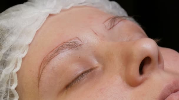 美容師は彼の患者に眉の形を修正します。特殊な鉛筆で眉の輪郭をマーク — ストック動画