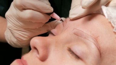 Güzellik uzmanı hastasına kaş düzeltmesi yapıyor. Kaşların dış hatlarını özel bir kalemle işaretliyorum.