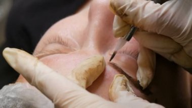 Ustanın eli kalıcı makyaj yapıyor. Toz püskürtme ile modern bir kaş düzeltme yöntemi. Mikroplu patinaj, kaş dövmesi