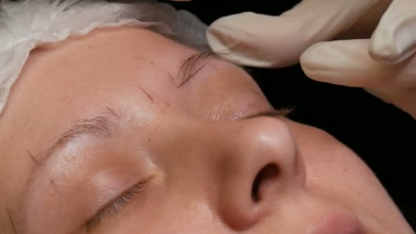 Beautician gör ögonbrynsform korrigering till sin patient. Märkning av ögonbrynens kontur med speciell penna — Stockvideo