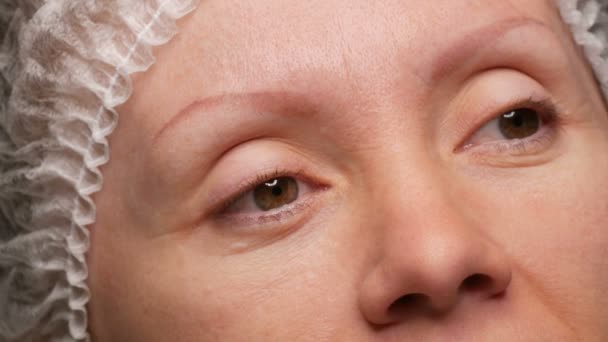 Quarenta jovens no estúdio de beleza antes do procedimento de correção de sobrancelha. Um rosto sem sobrancelhas, tatuagem de sobrancelha velha e desbotada. Microblading, tatuagem, pulverização em pó, maquiagem permanente — Vídeo de Stock