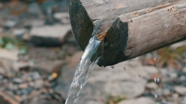 Een schone, transparante bergwaterstroom die van dichtbij door de houten goot stroomt — Stockvideo