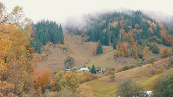 Ordinary Carpathian village in Ukraine. Thick fog over the top of Carpathian autumn mountains in colorful foliage in October. — Stock Video