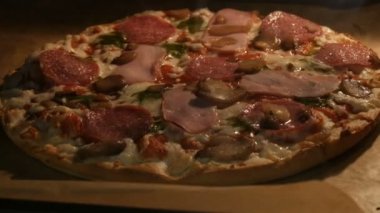 Mantarlı, salamlı, pastırmalı, otlu ve peynirli lezzetli pizza fırında pişiriliyor.