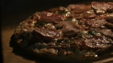 Mantarlı, salamlı, pastırmalı, otlu ve peynirli lezzetli pizza fırında pişiriliyor.