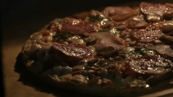 Deliciosa pizza com cogumelos, salame, bacon, ervas e queijo é cozida no forno — Vídeo de Stock